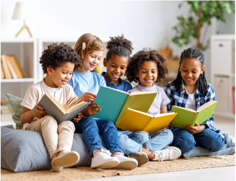 five children sitting on a bean bag reading together